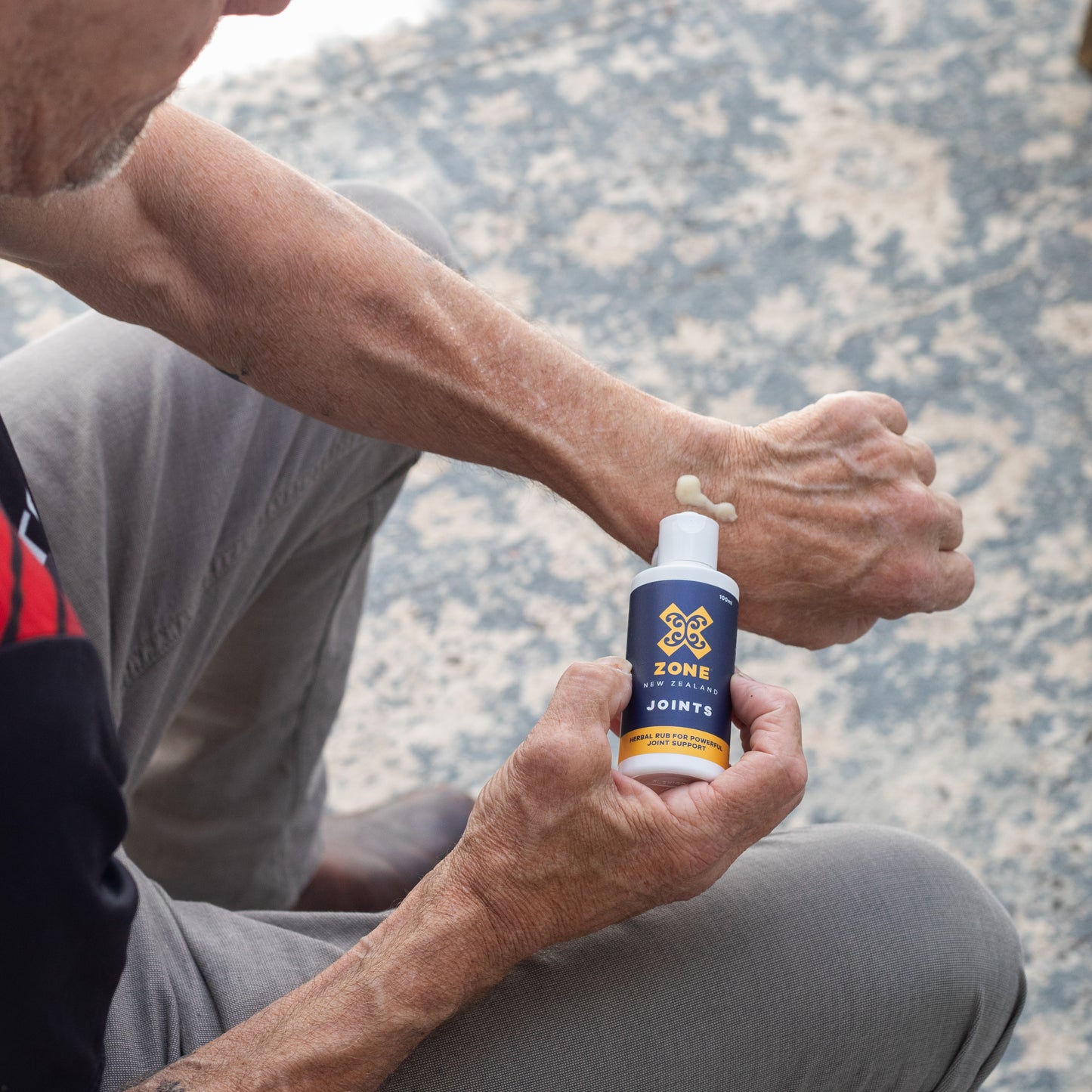 Sitting Man Applying X-ZONE JOINTS rub to wrist