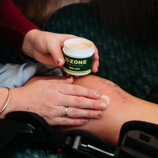 Person applying X-Zone Relief Rub New Zealand cream to a knee after surgery