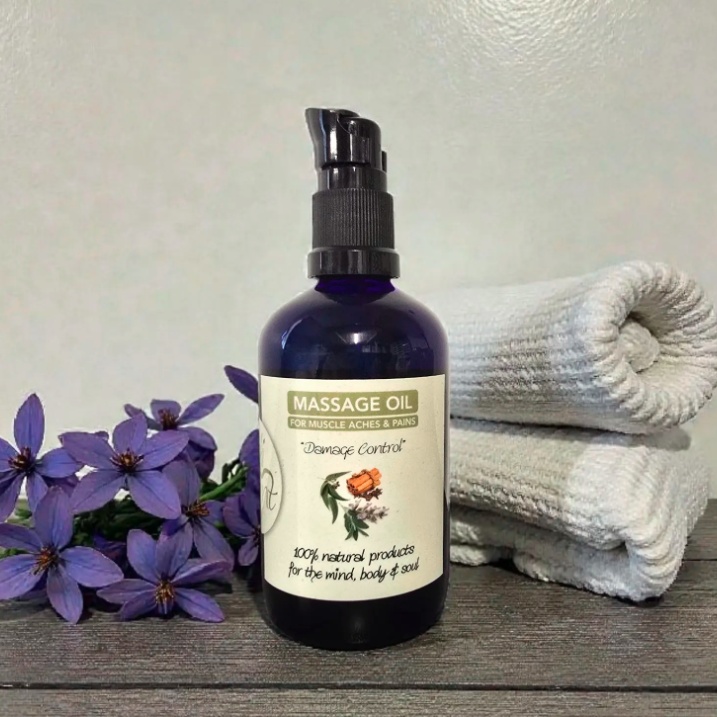 Massage oil bottle with flowers and towels on a wooden surface