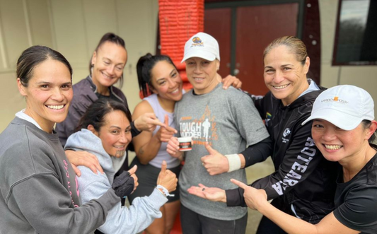 Huddle of Female touch rugby players pointing at a pot of X-ZONE Sports Rub